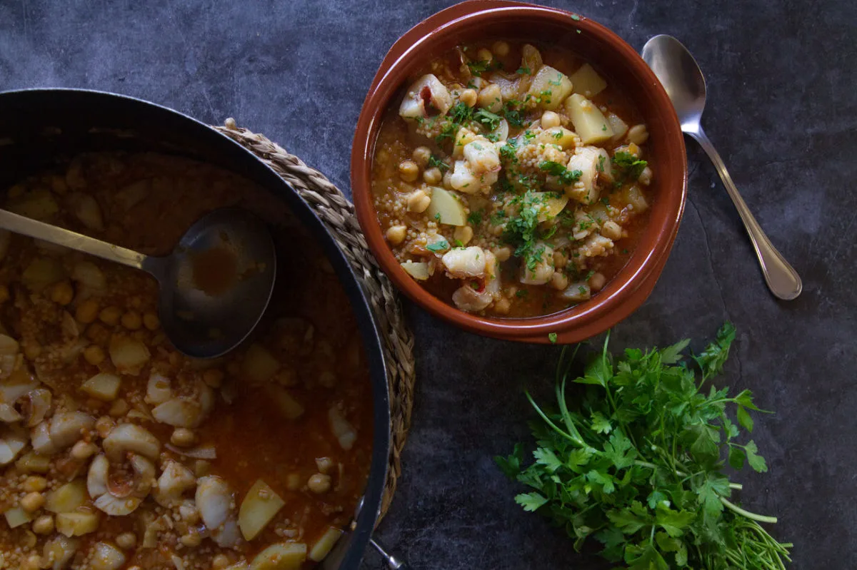 A small bowl of Fish stew is served rom a large pot.