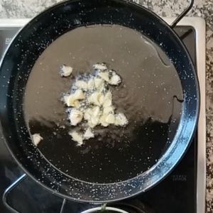 Some sliced garlic cooks inn a pan witth some olive oil.