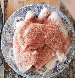 Some chicken pieces covered in paprika and salt.