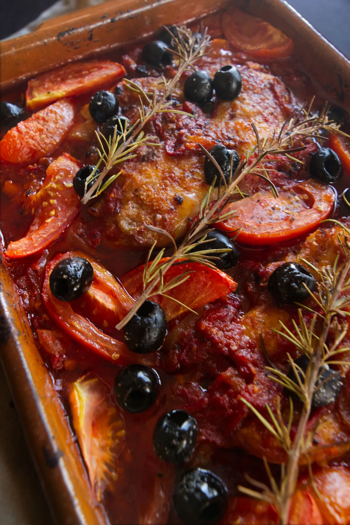 A large casserole dish of Mediterranean boneless chicken thighs with a rich red sofrito sauce.