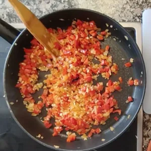 Some onion and red pepper simmer in a large skillet.