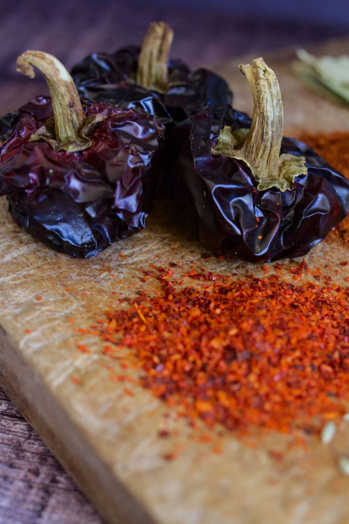 whole Nora peppers sit beside some some ground Nora pepper flakes. 