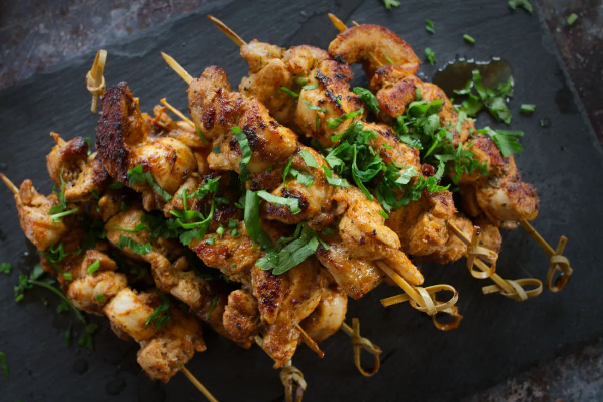 paprika-chicken-hero-v1-1200x800 A small pile of paprika-infused chicken skewers sit on a slate plate.
