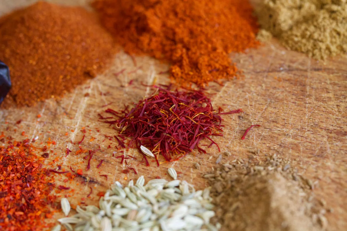 A small pile of saffron threads beside other Spanish spices.