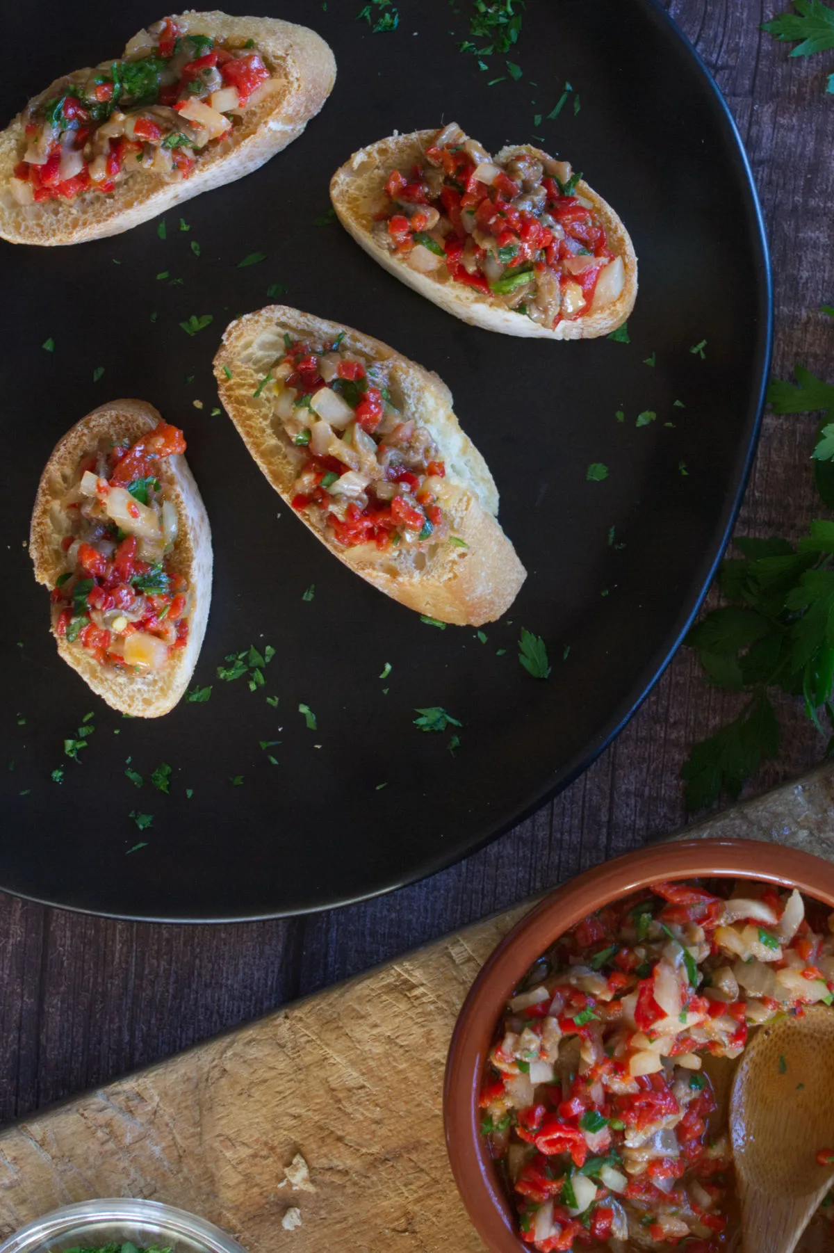 A small bowl of anchovy and pepper spread sists next to some served canapes. 