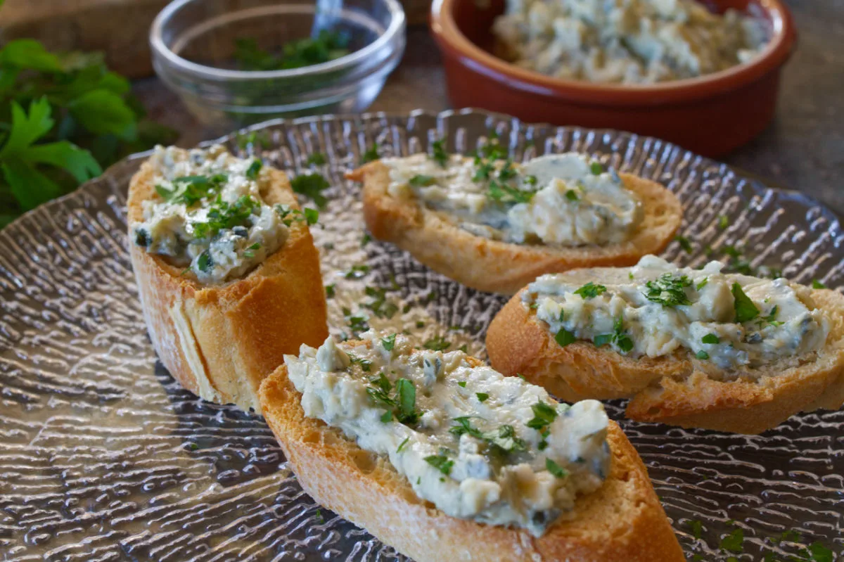 Some tapas servings of blue cheese and cherry spread served on top of toasted bread.