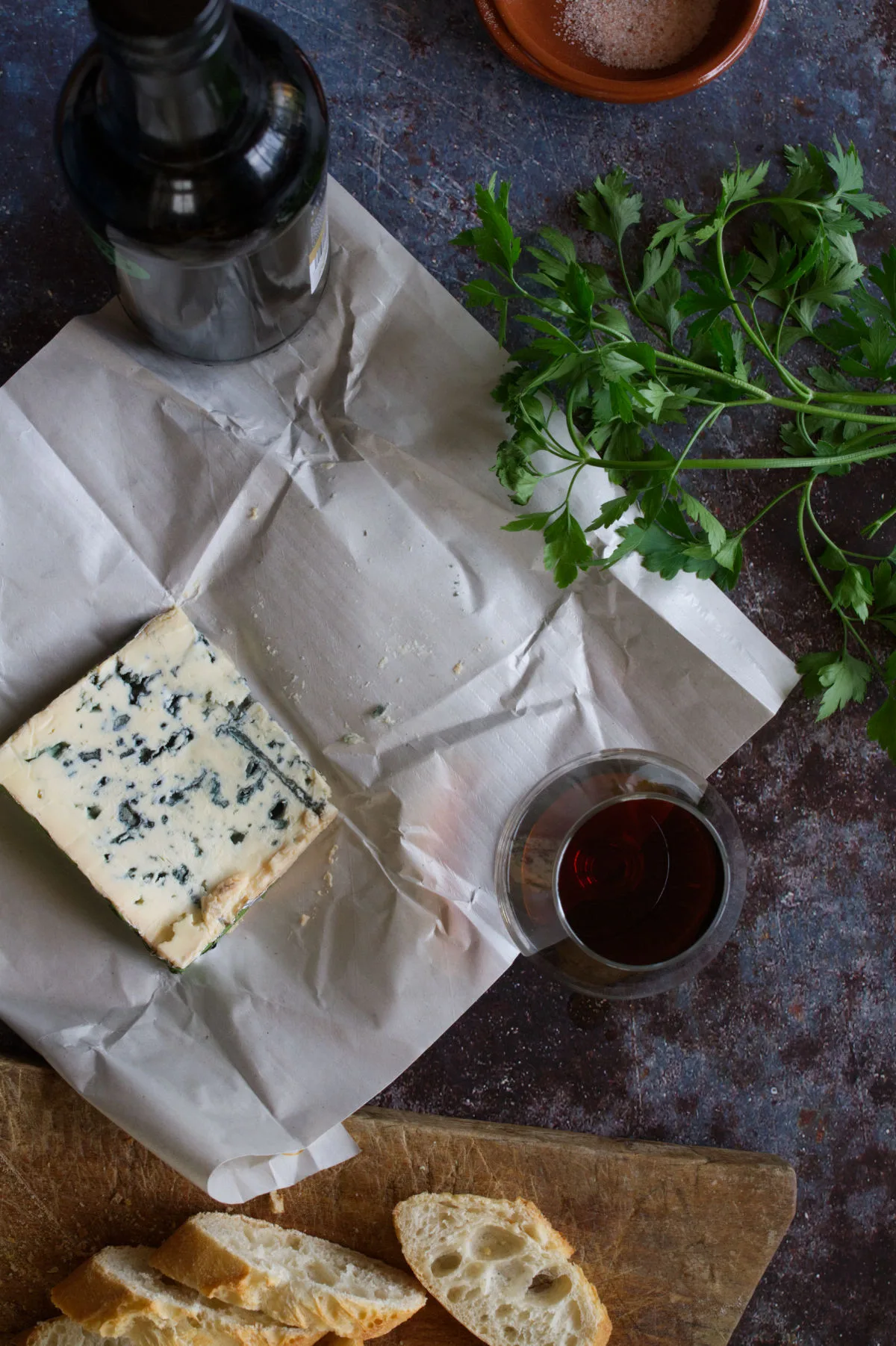 A wedge of Blue cheese sits next to a small glass of sherry. 