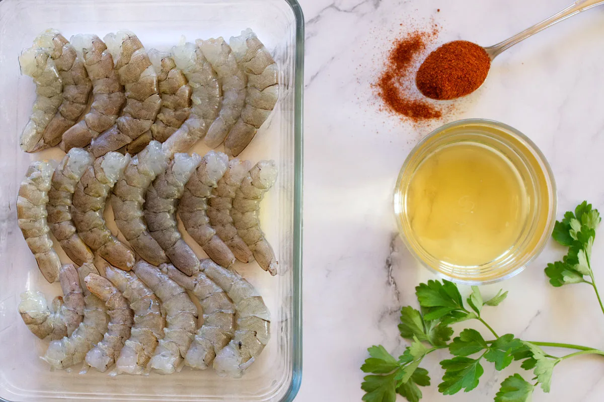 Shrimp are laid out beside some paprika, parsley, and a glass of Cava.