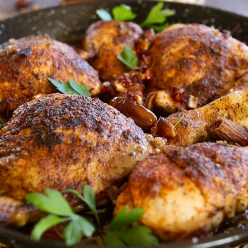 Mediterranean-style crispy chicken pieces in a deep pan with some fresh parsley.