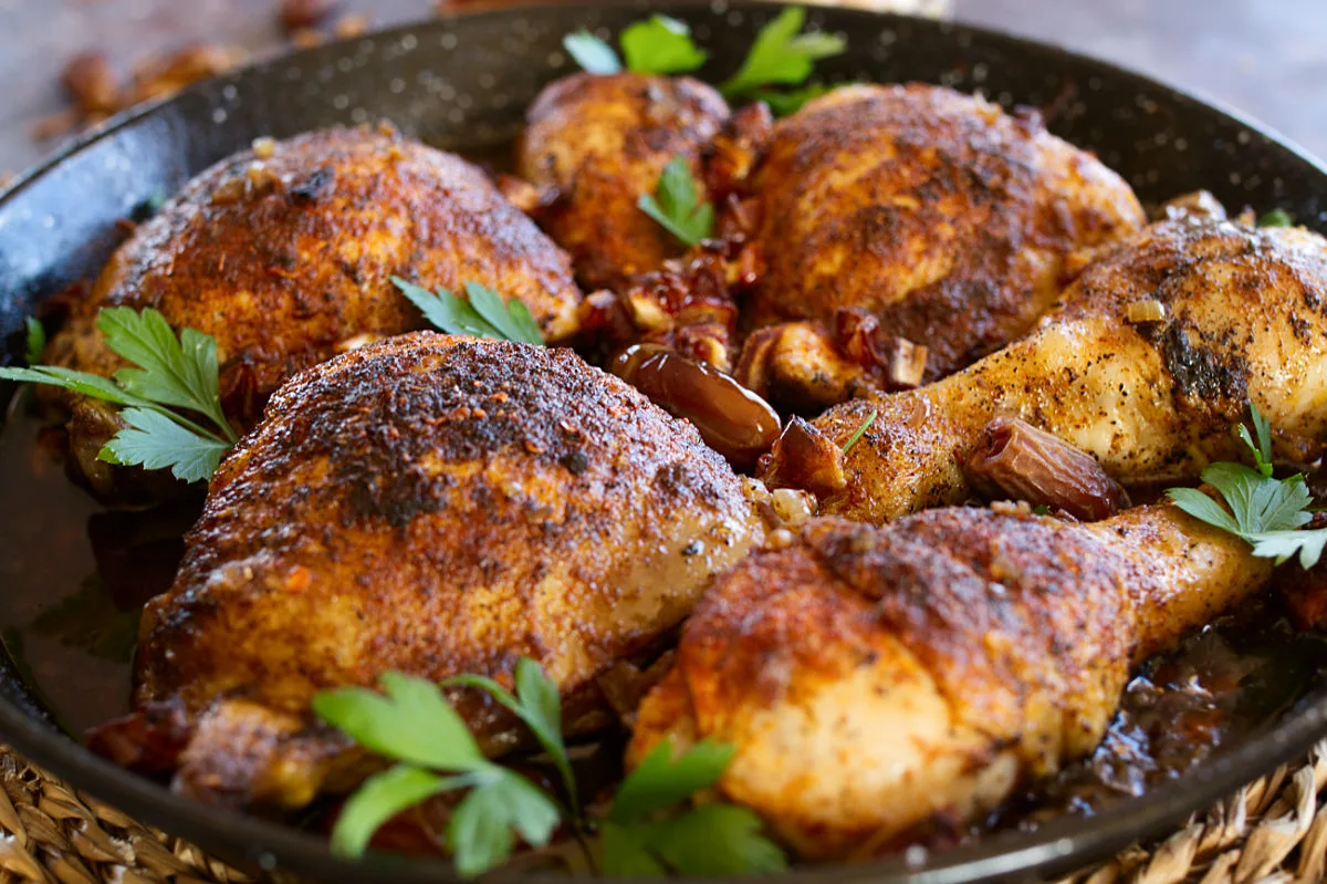 Mediterranean-style crispy chicken pieces in a deep pan with some fresh parsley.