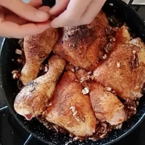 Dried dates are scattered around some pan-fried chicken pieces.