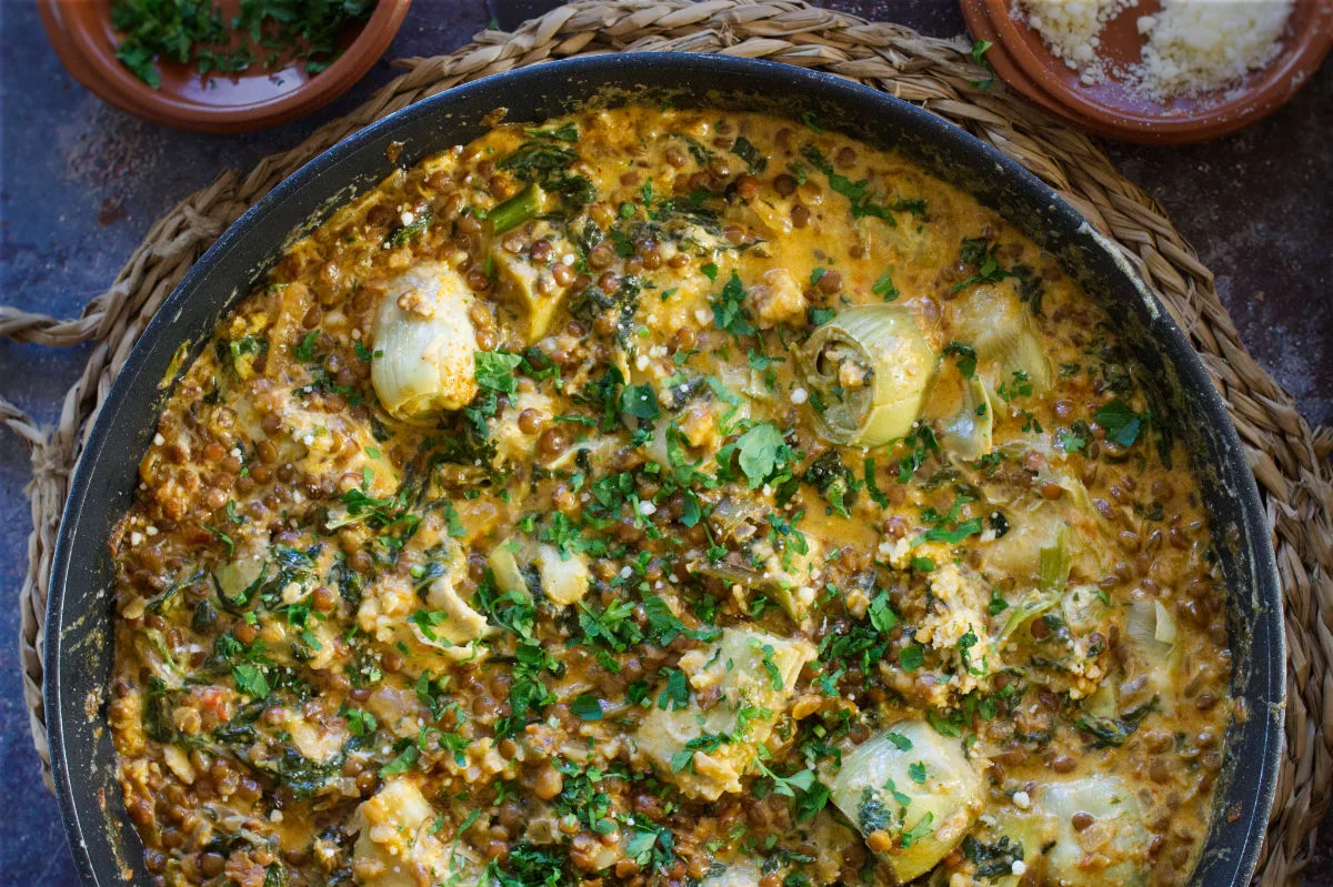 A pan of creamy artichoke casserole with spinach and paprika.