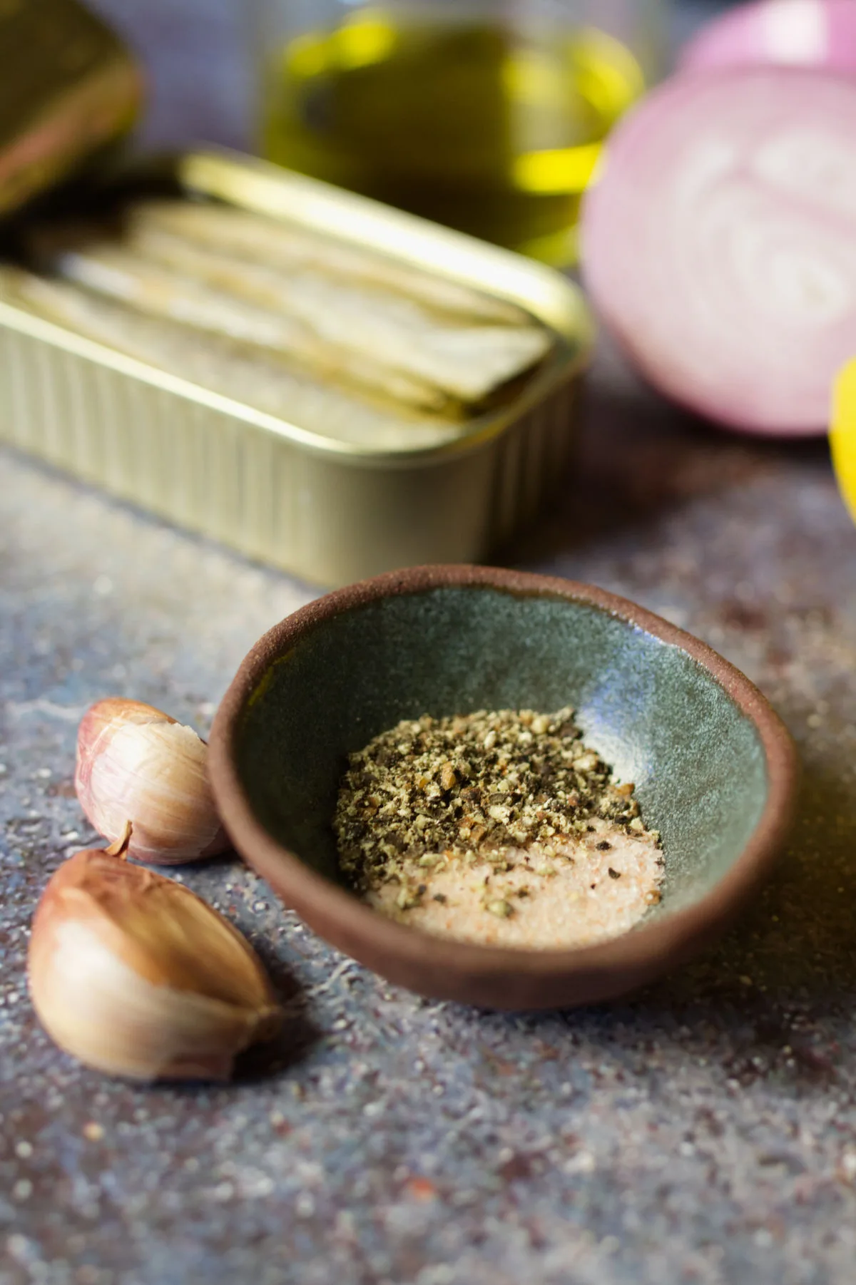 A small bowl of seasoning sits beside some sardines