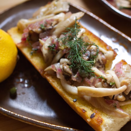 a plate of mushroom on toast with fennel and red onion.
