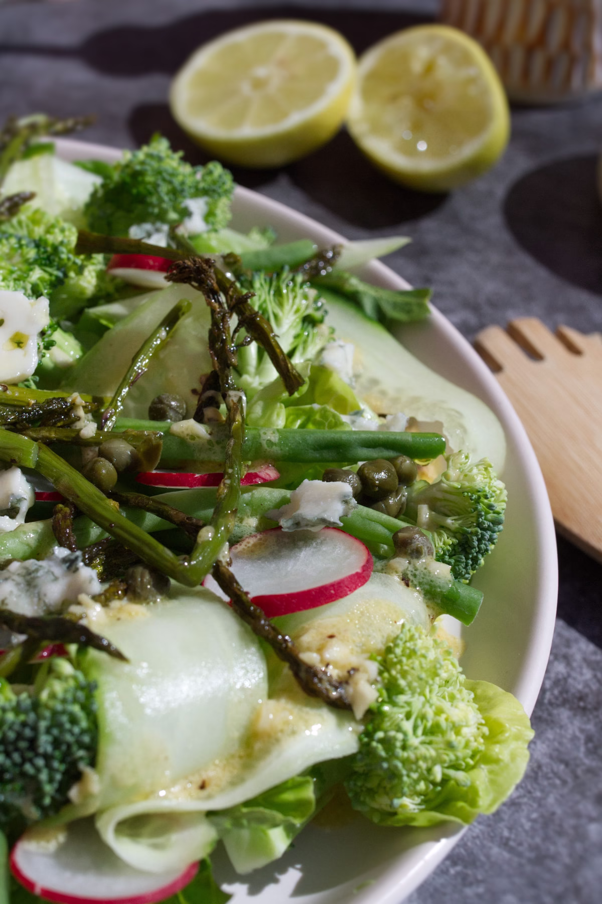 A plate of Spanish Green salad sits beside some fresh lemon.