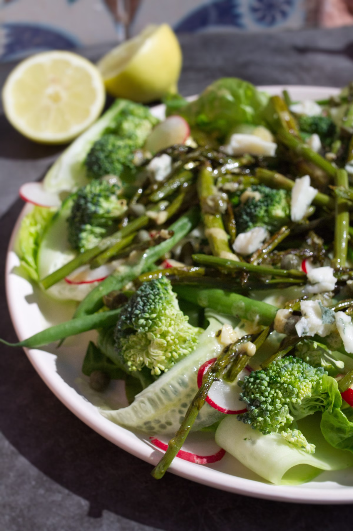 A plate of Spanish Green salad sits beside some fresh lemon.