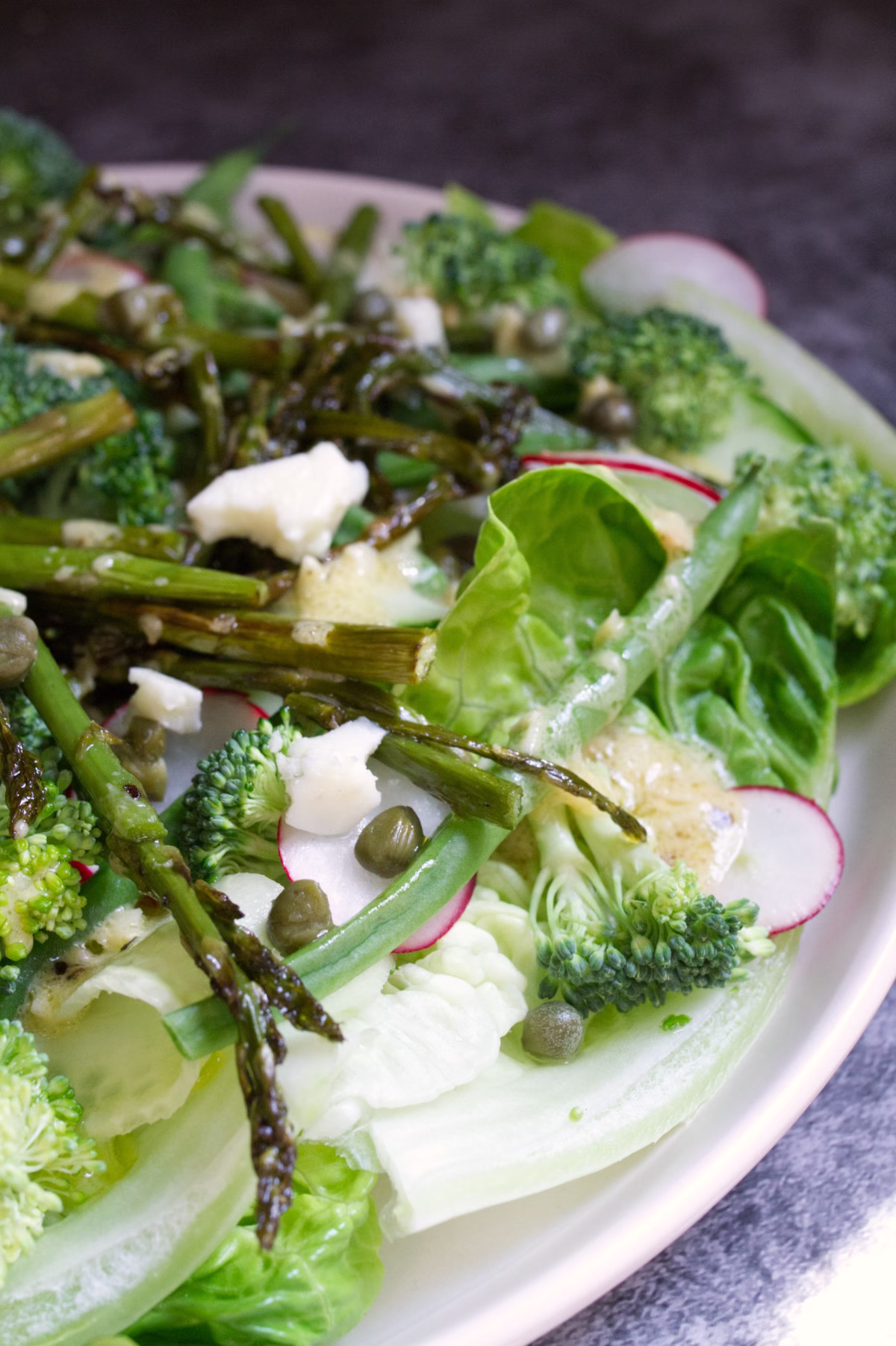 A plate of Spanish Green salad sits beside some fresh lemon.