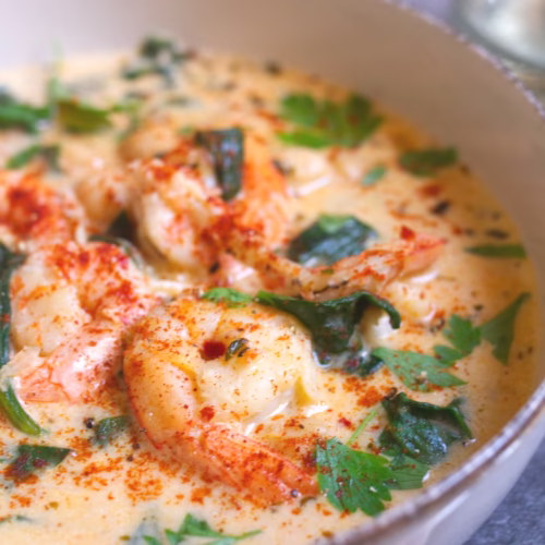 A bowl of creamy shrim soup with spinach and chickpeas is garnished with some fresh parsley