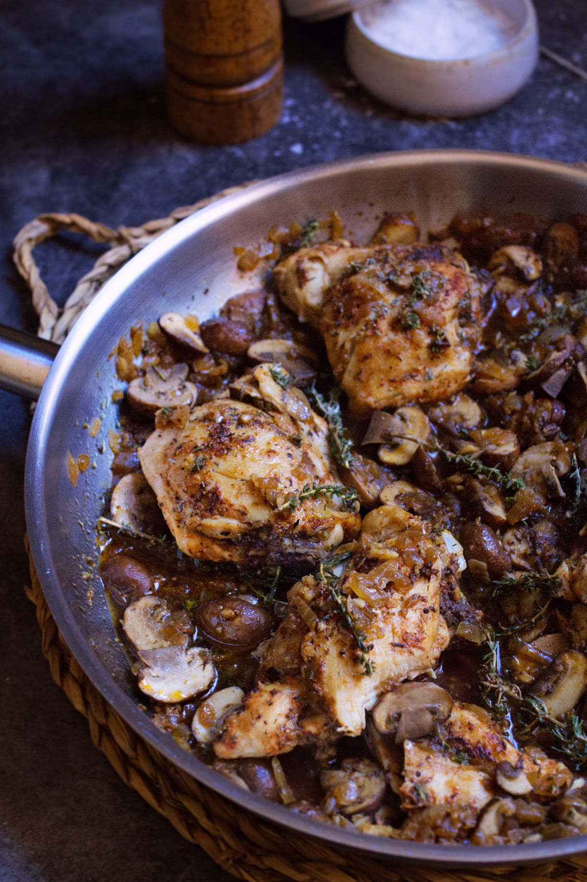 A pan of garlic mushroom chicken thighs with fresh thyme garnish