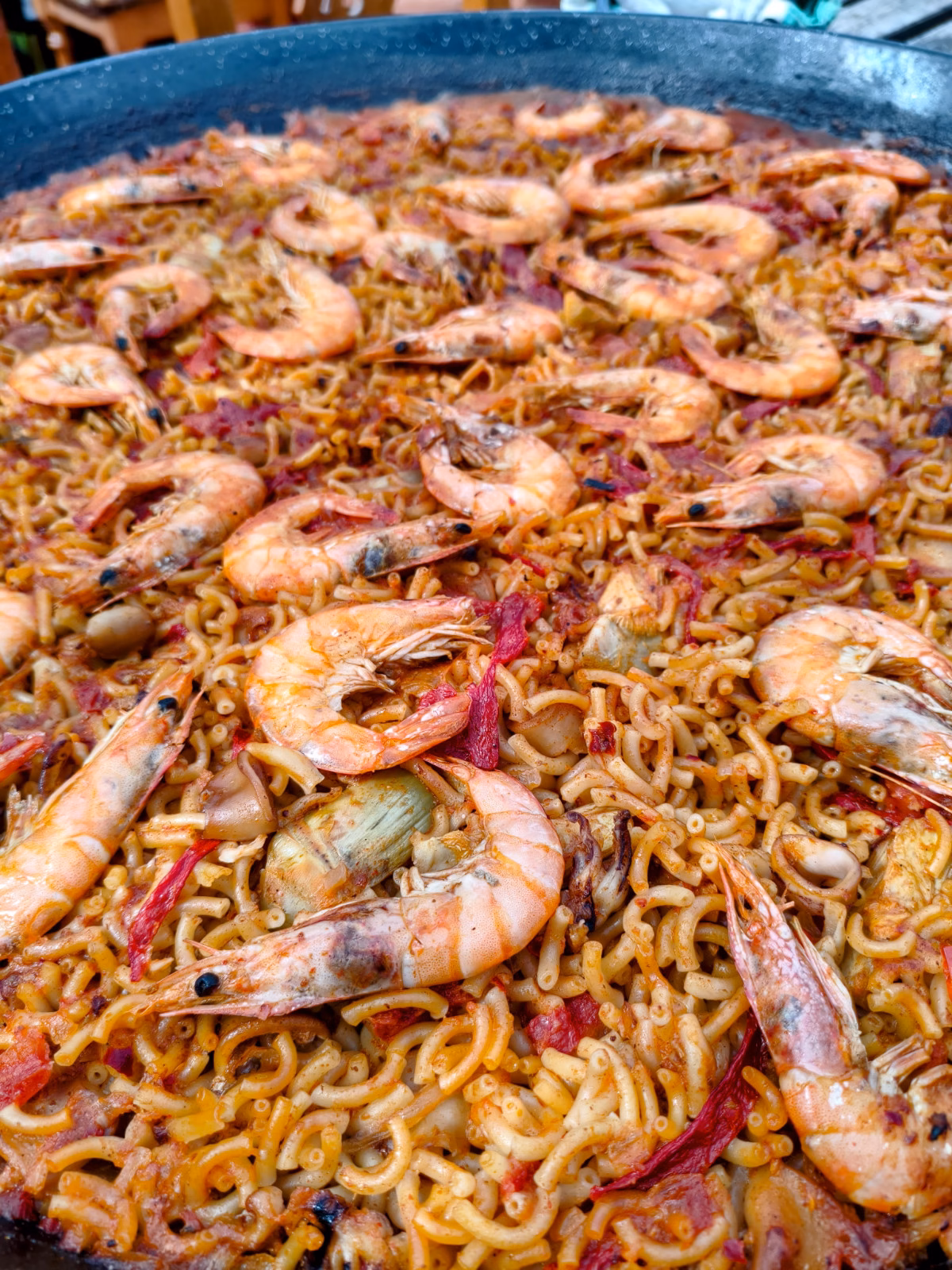 A large pan of seafood fideua topped with prawns