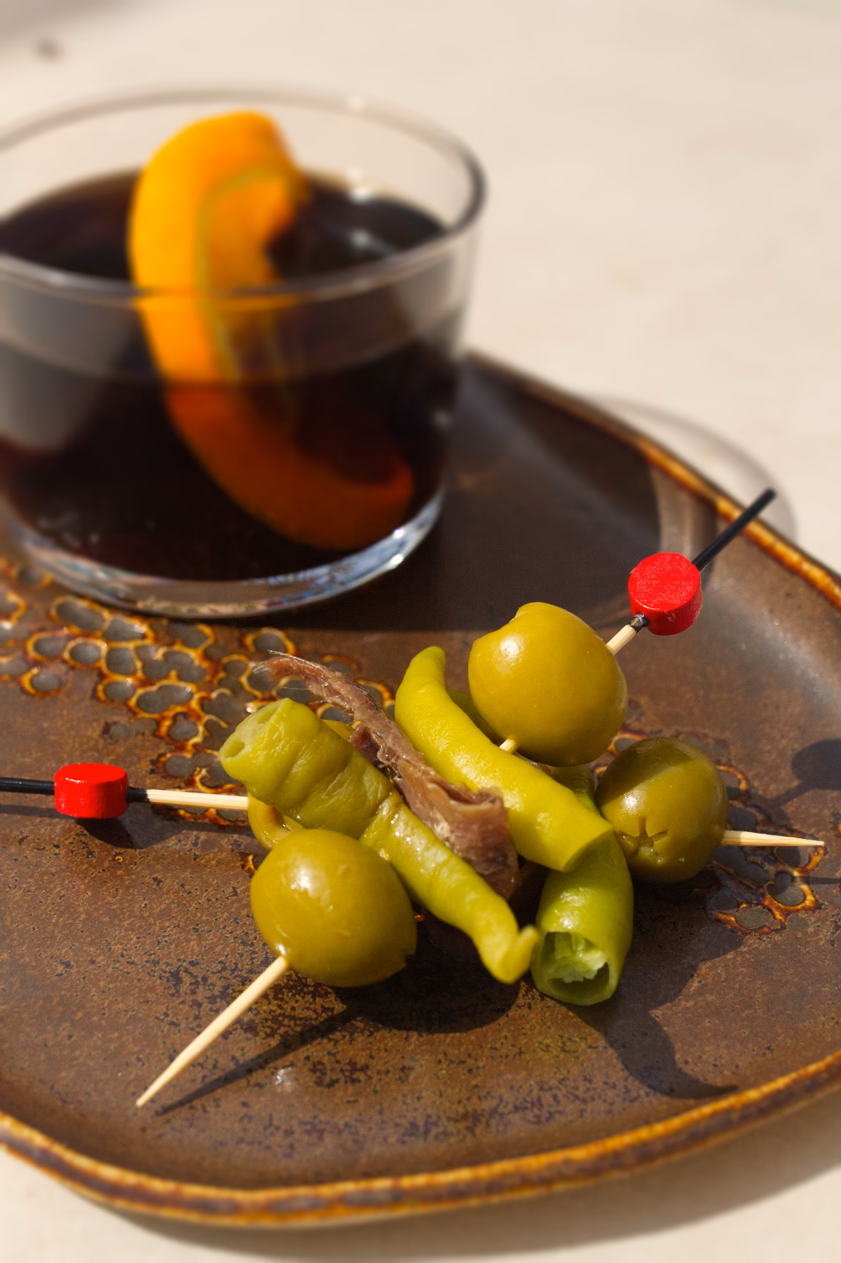 2 Gildas next to a small Spanish vermouth garnished with orange