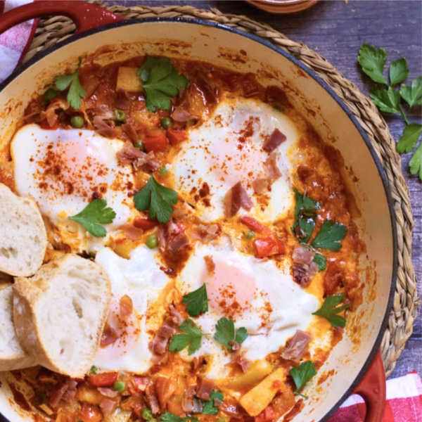 Flamenco eggs recipe cooked in a pot and ready to serve with a few sprinkles of parsley on the top.