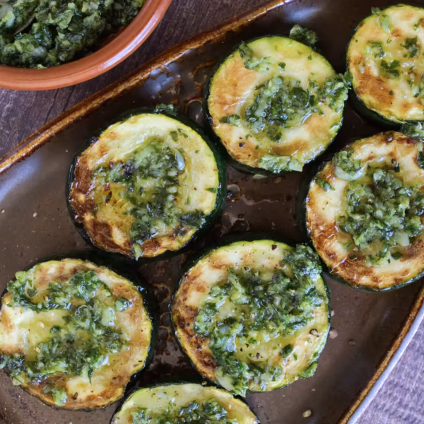 Cooked zucchini rounds topped with garlic, parsley, and olive oil.