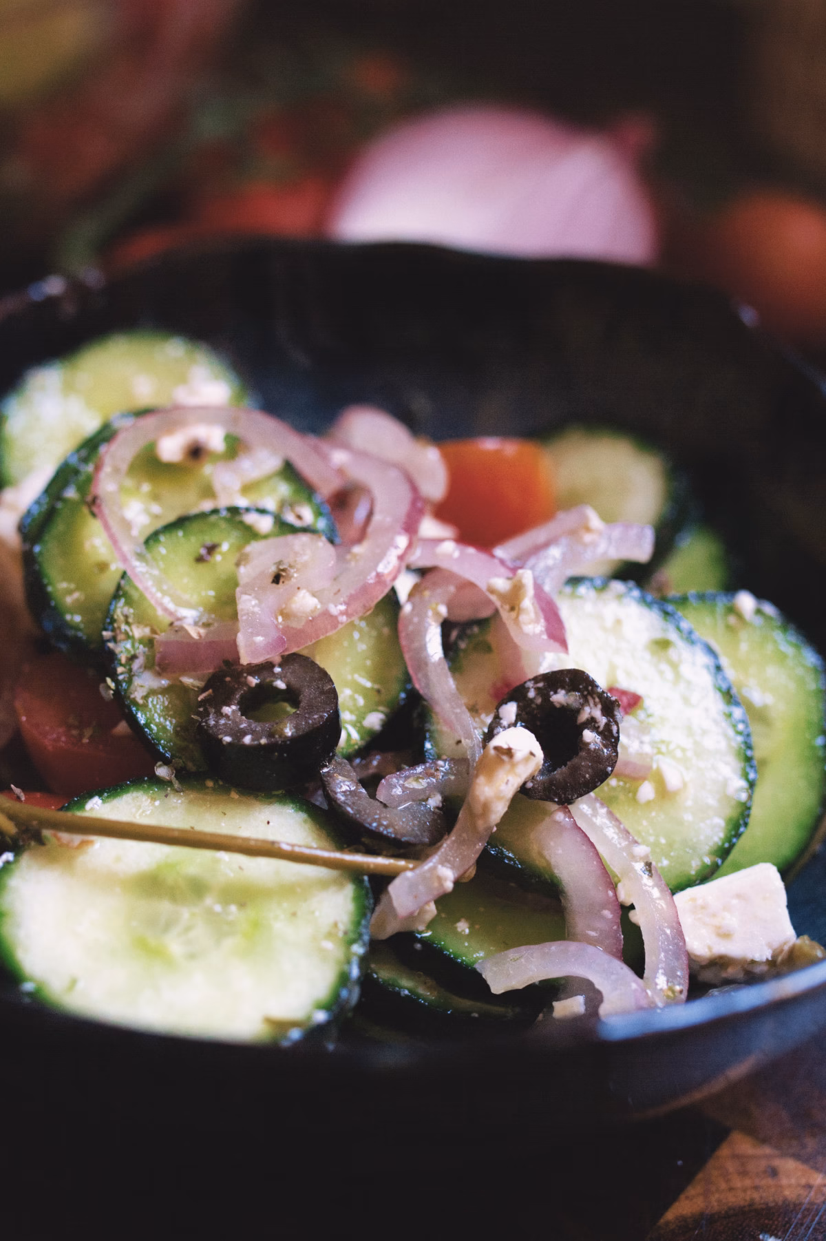 A close up shot of a Mediterranean cucumber salad in a blue bowl