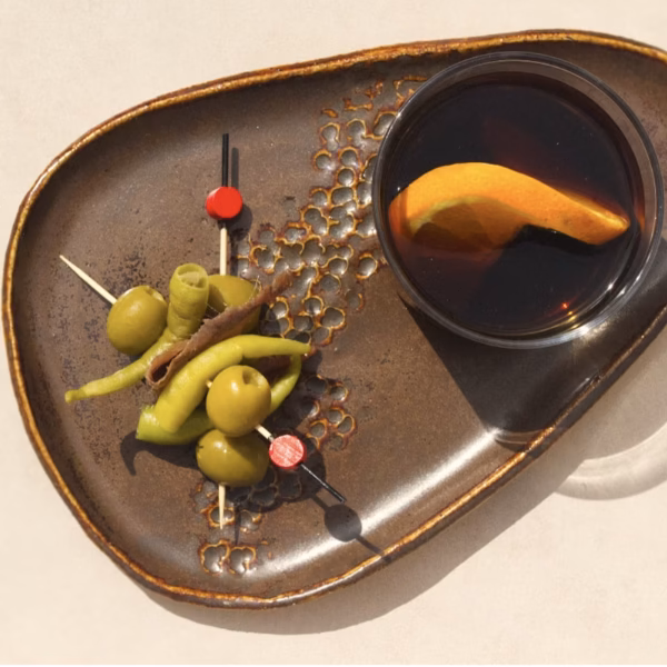 Two gildas on a serving plate next to a glass of red vermouth.
