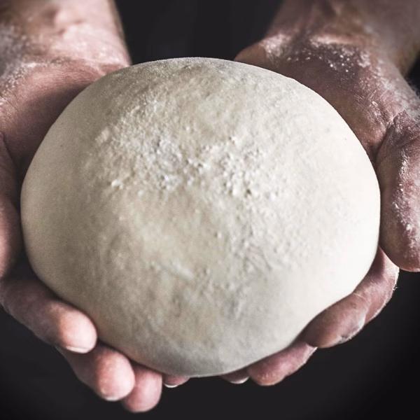 Hands holding out a ball of vegan empanada dough.