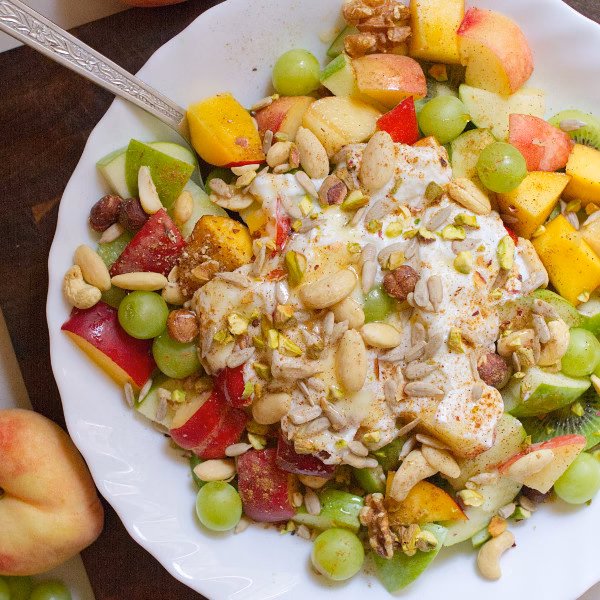 A bowl of Mediterranean fruit salad topped with yogurt and nuts