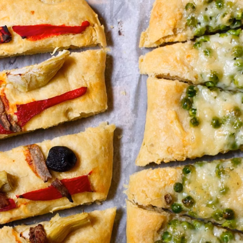 2 Spanish cocas with different toppings - one with red pepper and the other with peas and cheese