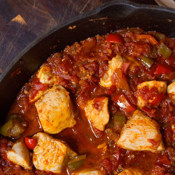 A large pan of Spanish chicken with tomato sauce
