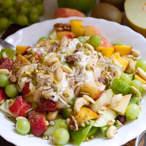 mediterranean-fruit-salad-v29 - The Spanish Radish A bowl of freshly prepared Mediterranean fruit salad garnished with yogurt, nuts, and seeds