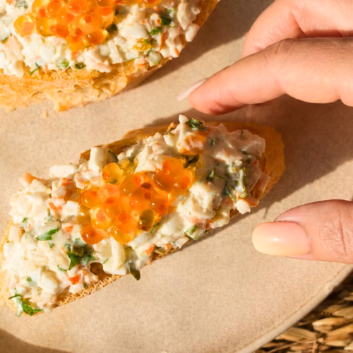 A person reaches in to grab a Txaka Pintxo on a plate