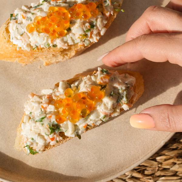 A person reaches in to grab a Txaka Pintxo on a plate