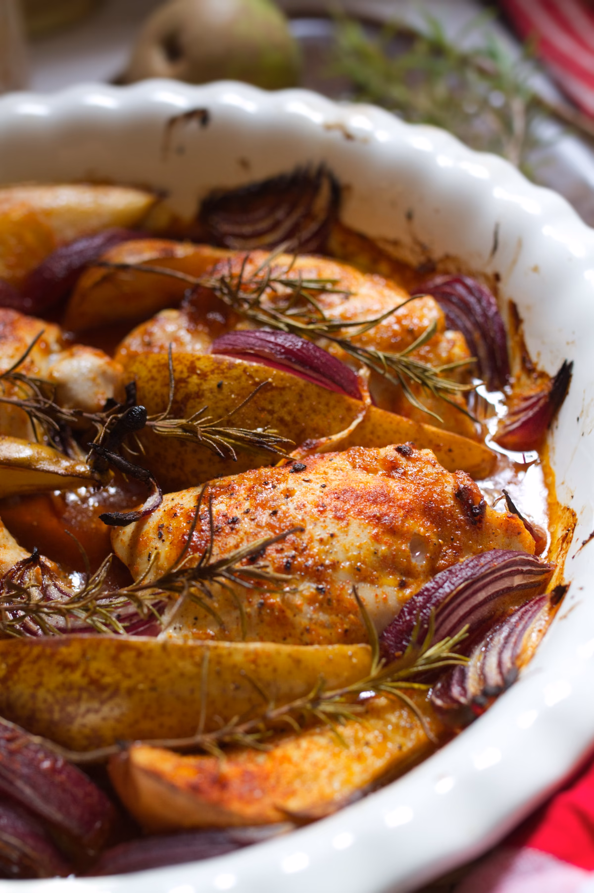A large pan of baked Chicken thighs with Spiced pears and rosemary garnish