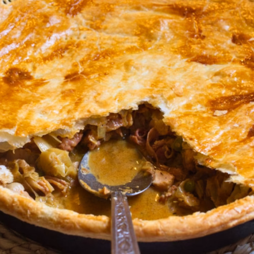 A large Spanish chicken and leek pie with a slice removed